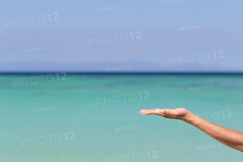 Hand holding nothing with ocean background