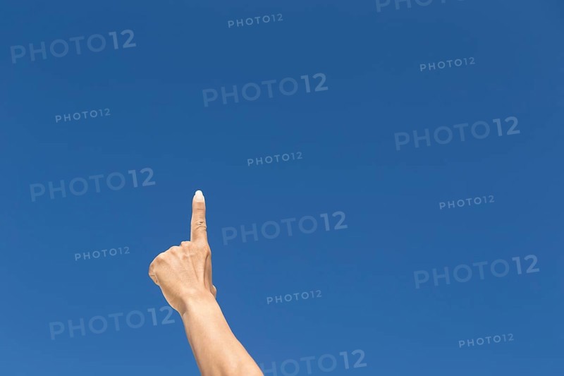 Finger raised against blue sky