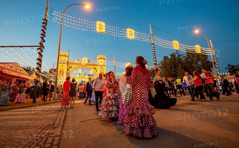 Spanish women with flamenco dresses in front of the illuminated Portada