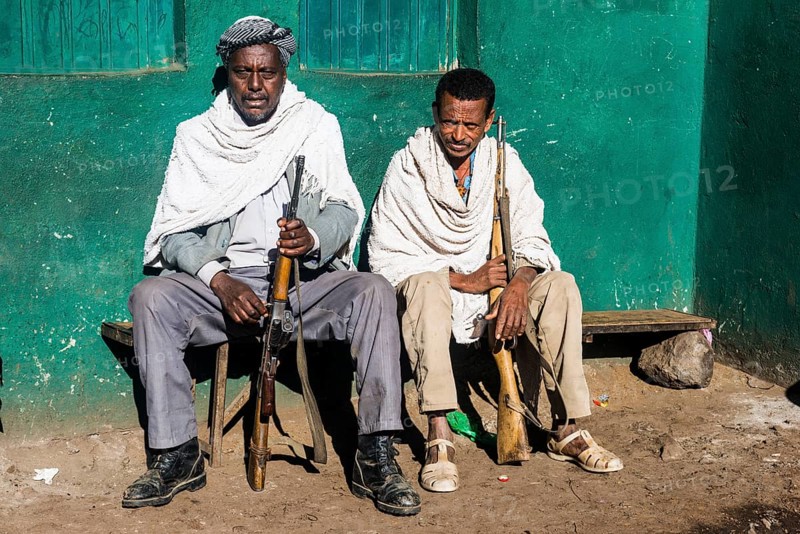 Two sentries with rifles sitting on a bench