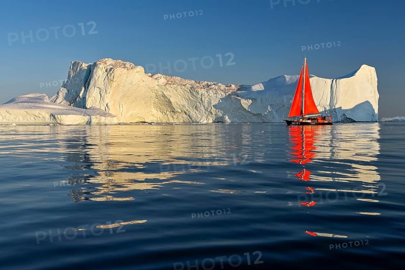 Red sailing boat in front of icebergs