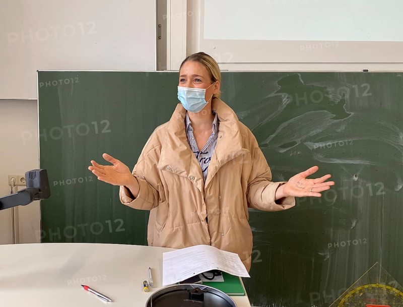 Teacher with thick winter jacket and face mask in classroom teaching