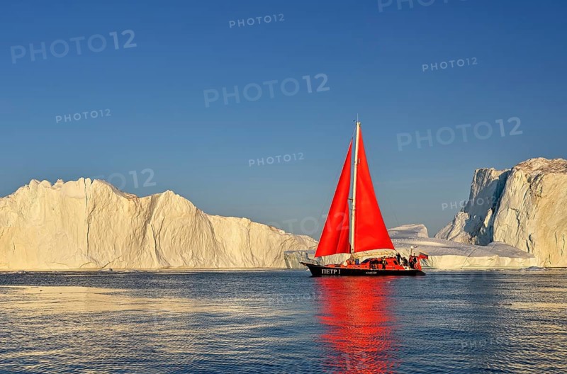 Red sailing boat in front of icebergs