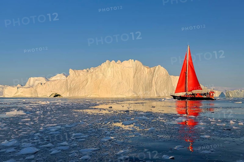 Red sailing boat in front of icebergs
