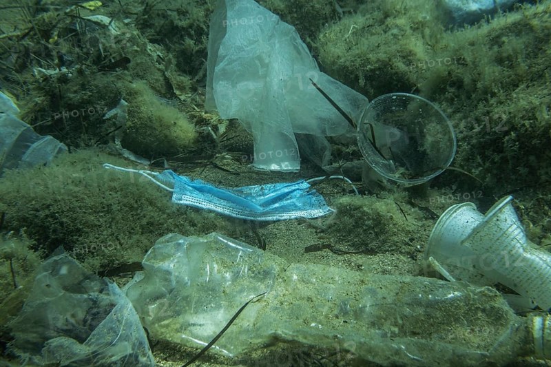 Discarded used medical face mask along with other plastic debris lies on the seabed. Plastic and other garbage polluting in the Adriatic Sea. Becici