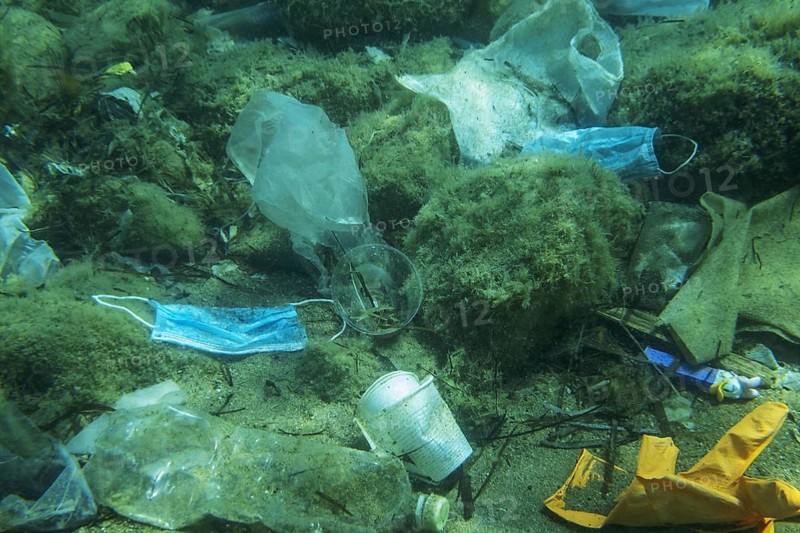 Discarded used medical face mask along with other plastic debris lies on the seabed. Plastic and other garbage polluting in the Adriatic Sea. Becici