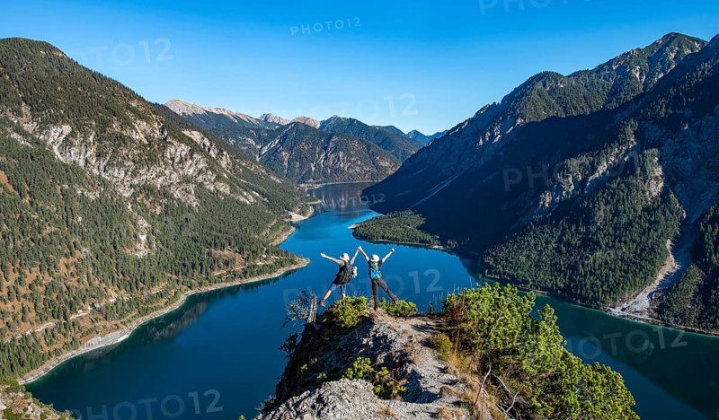 Two hikers stretch arms in the air