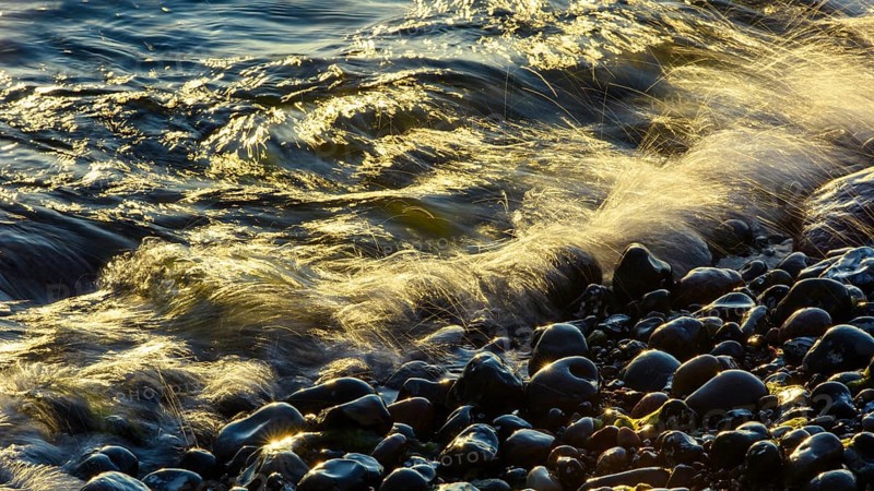 Waves and spray on the beach at sunrise