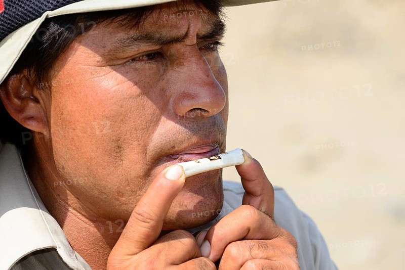 Indigenous man plays on a bone flute