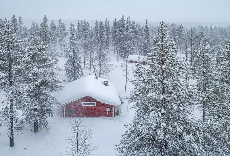 Red wooden house in the forest with snowfall in winter