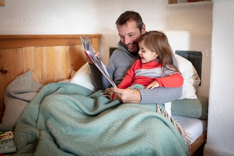 Father reading aloud with daughter