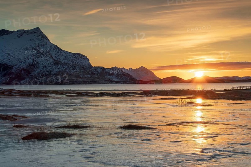 Sunset at sandy beach covered with ice
