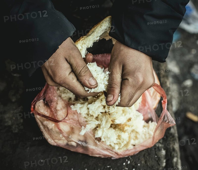 Escaped man plucks stale bread for a meal