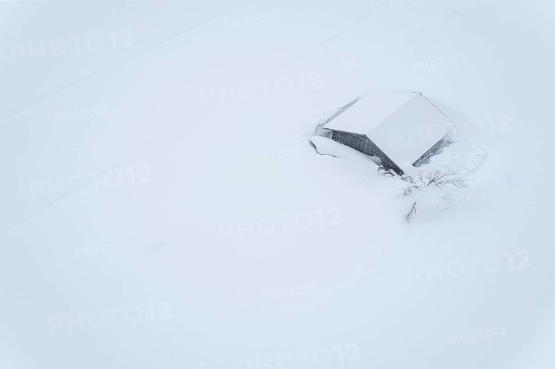Aerial view of a lonely wooden house in the snow in winter