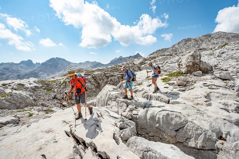 Three hikers in a landscape of washed-out karst rocks