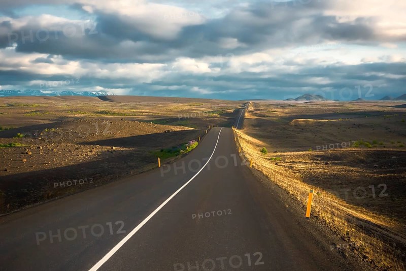 Road in the evening light runs through vuclan plateau with lava rock in the Krafla