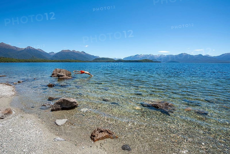 Young man jumps from stone into water