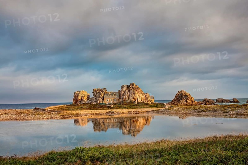 House between granite rocks with water reflection