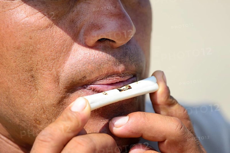 Indigenous man plays on a bone flute