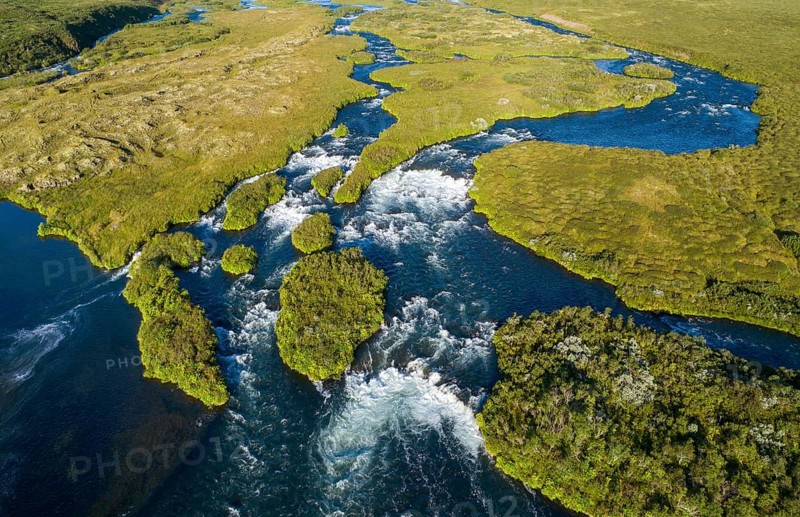 Aerial view of small green grass-covered islands in the river Laxa i Aoaldal