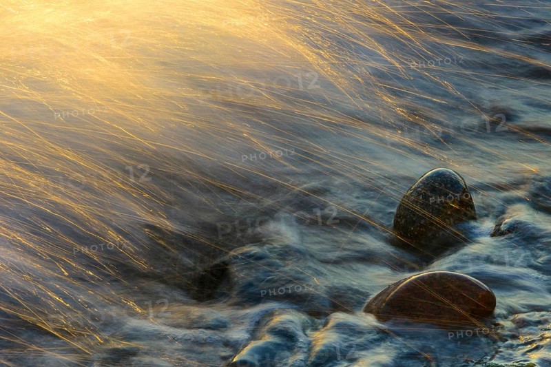 Waves and spray on the beach at sunrise