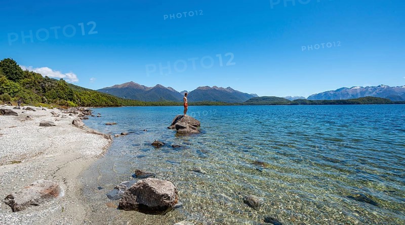 Young man standing on stone in water