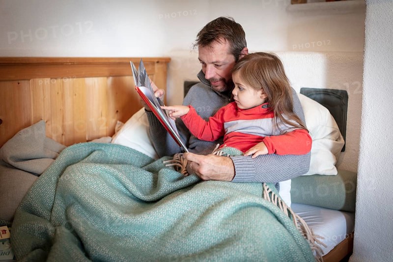 Father reading aloud with daughter