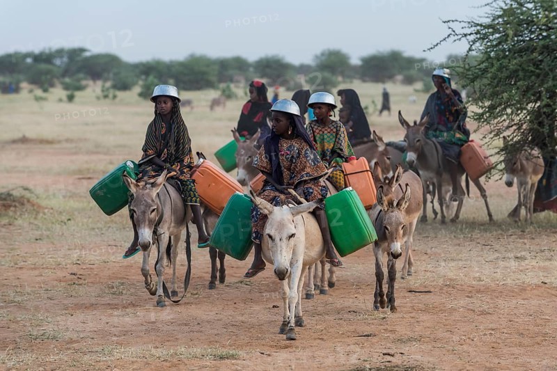Young girls on donkeys on their way to a waterhole