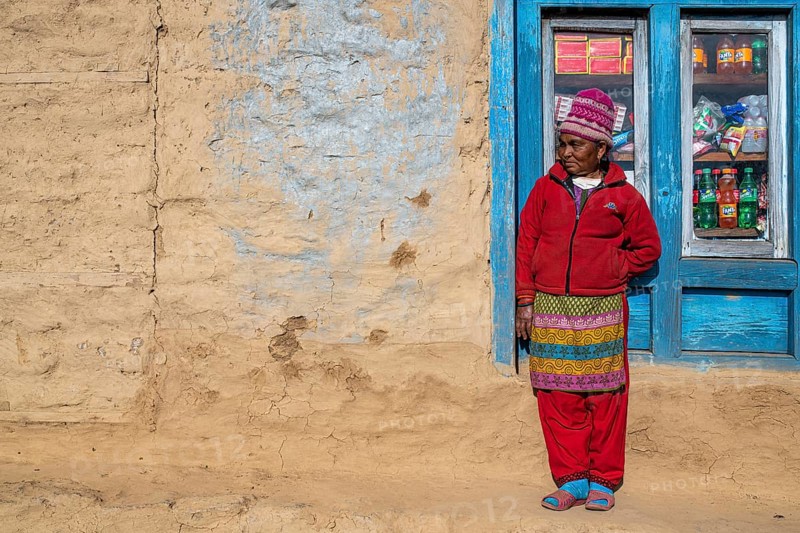 A local woman is standing in front of the window of her shop