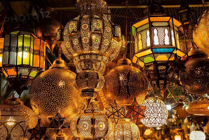 Various lamps made of brass or copper and colored glass for sale hung up