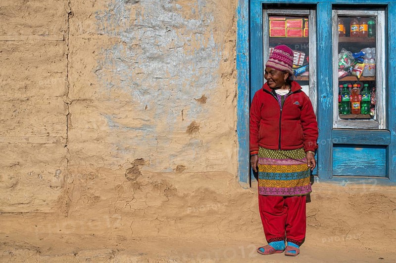 A local woman is standing in front of the window of her shop