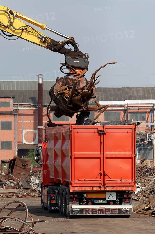 Excavator loads metal scrap onto truck