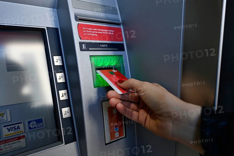 Woman introduces ec-card at the cash dispenser of a savings bank