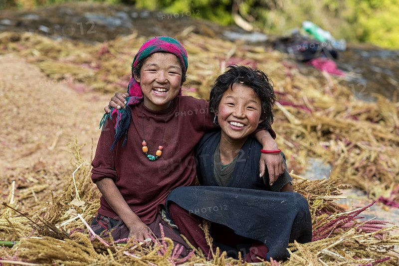 Two happily laughing children sitting in a pile of pearl millet