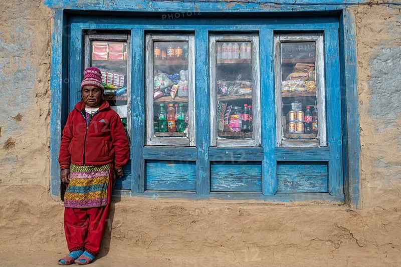 A local woman is standing in front of the window of her shop