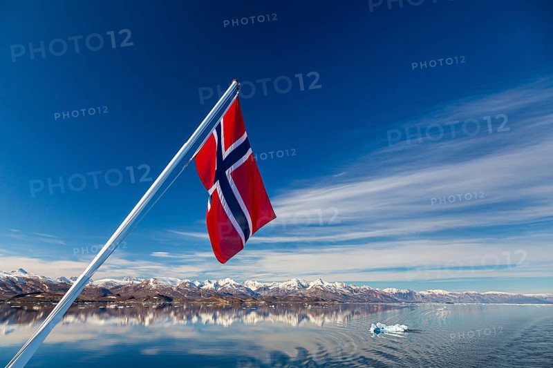Norwegian flag waving over fjord in Greenland