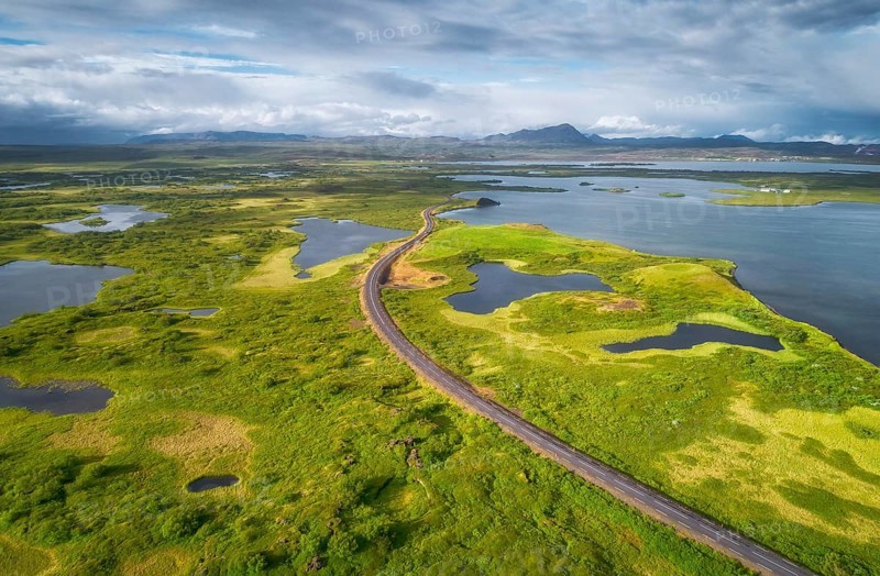 Aerial view of road through green landscape with volcanic crater