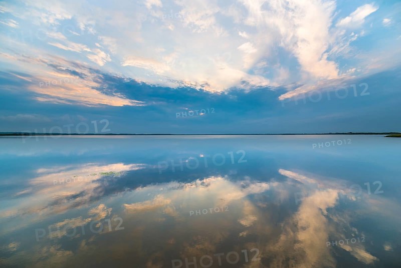 Clouds reflected at sunrise on the smooth lake