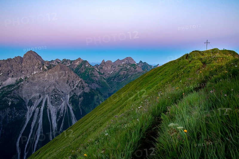 Small mountain trail with flower meadow and summit of the Uentschenspitze at sunrise