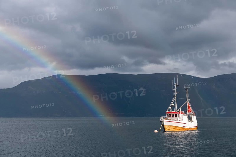 Fishing boat in fjord with rainbow