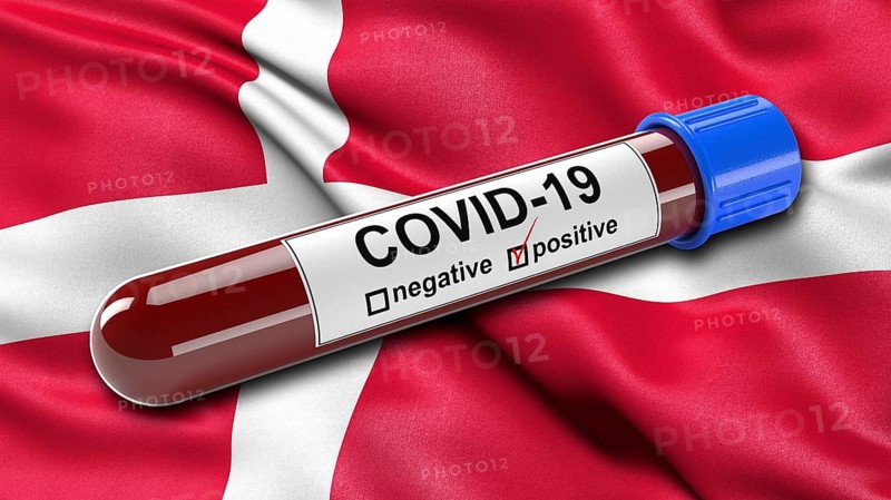 Flag of Denmark waving in the wind with a positive Covid-19 blood test tube. 3D illustration
