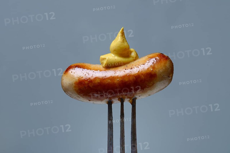 Chipolata sausages with mustard on fork