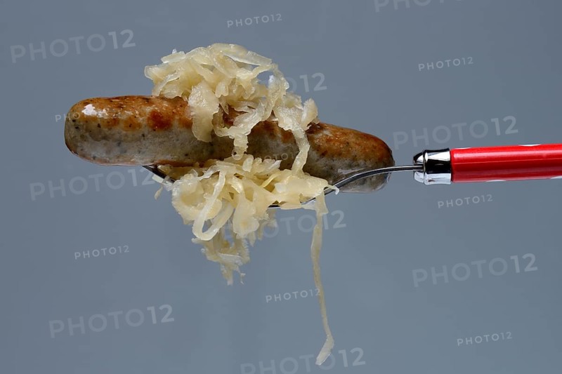 Nuremberg grilled sausages with sauerkraut on fork