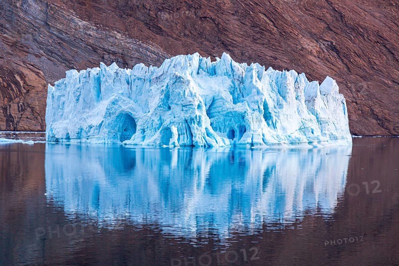 Iceberg in front of rock in fjord
