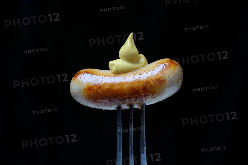 Chipolata sausages with mustard on fork