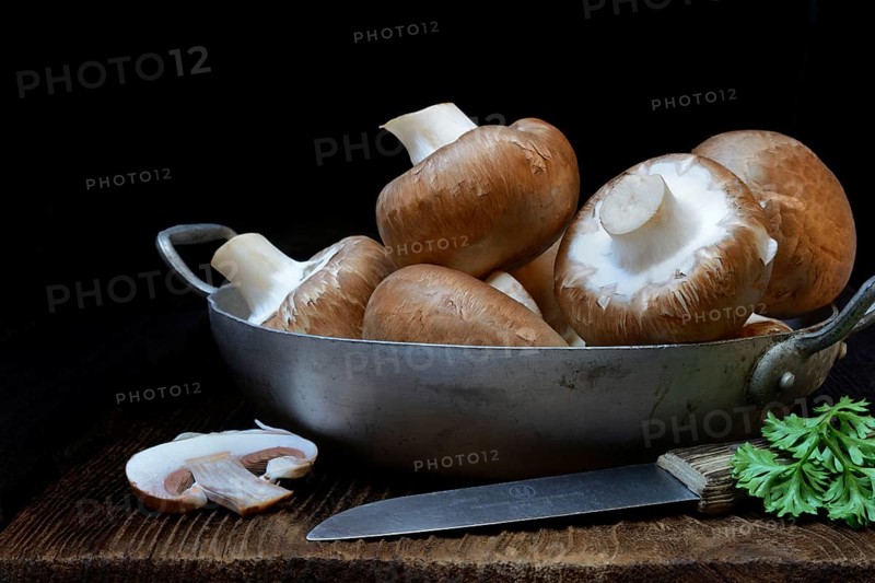 Brown cultivated mushrooms in shell with knife
