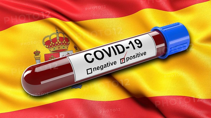 Flag of Spain waving in the wind with a positive Covid-19 blood test tube. 3D illustration