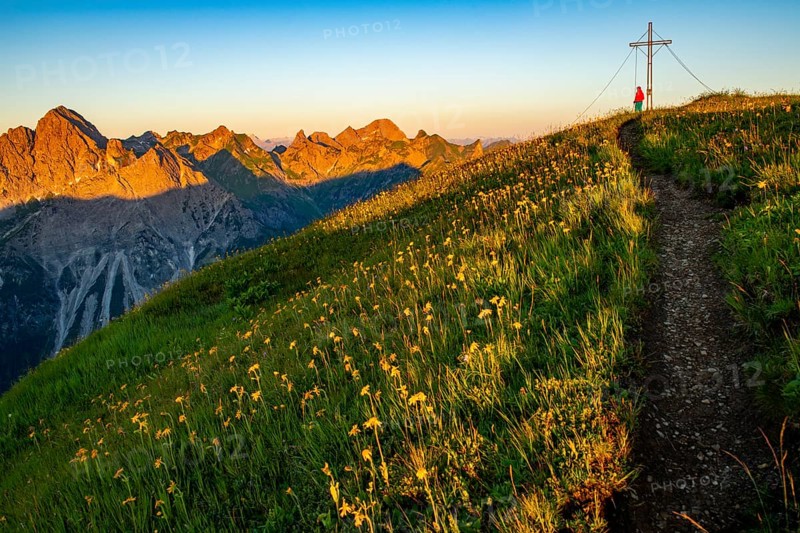 Small mountain trail with mountaineer and summit of the Uentschenspitze at sunrise