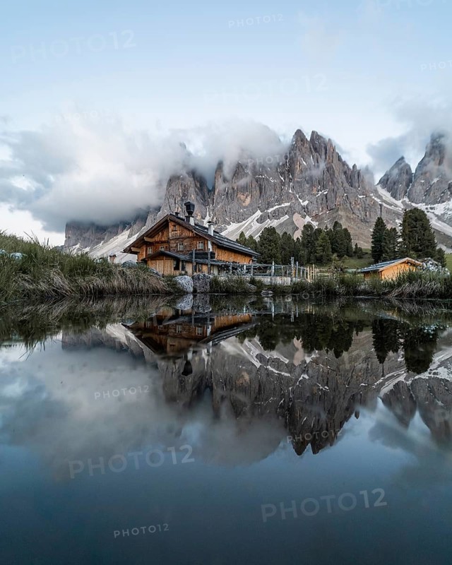 Reflection from the Furchetta mountain and the Geisler Alm hut in a pond near the Geisler Alm
