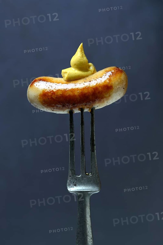 Chipolata sausages with mustard on fork